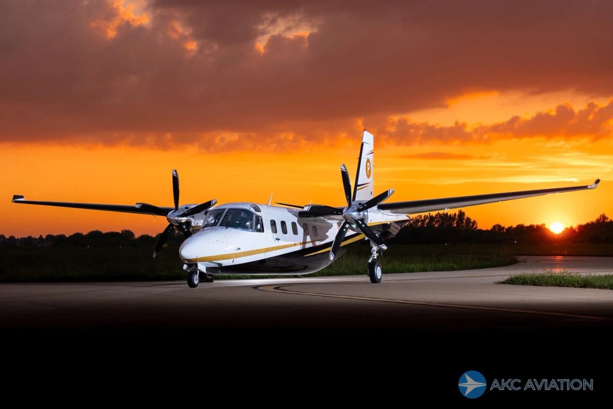 A Twin Commander aircraft on the tarmac at sunset.