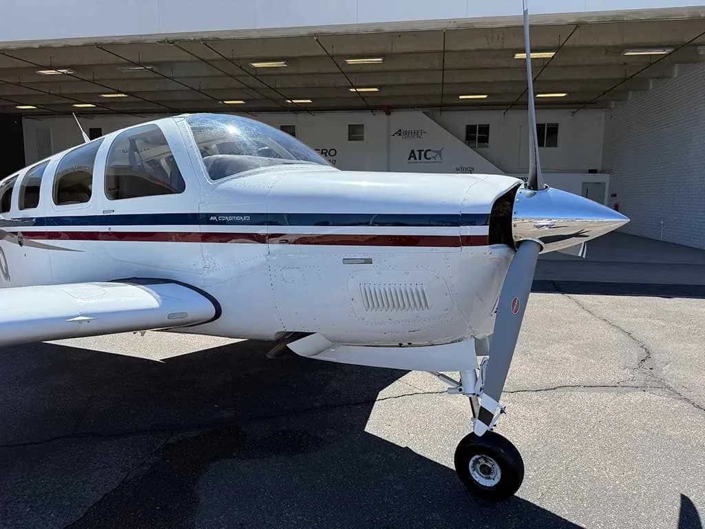 A close-up view of the nose and propeller of the white Beechcraft Bonanza A36, registration N25Q, with its polished spinner.