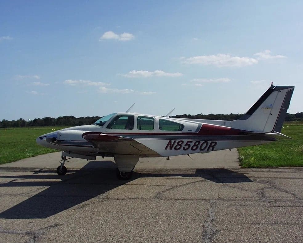 Side view of a white and maroon aircraft with tail number N8580R on a paved surface.