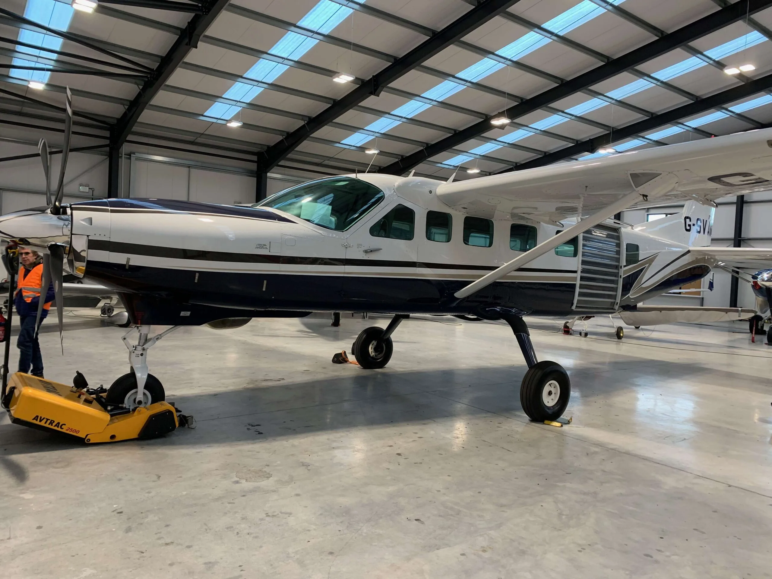 A Cessna Caravan aircraft with a blue and white paint scheme parked in a hangar.