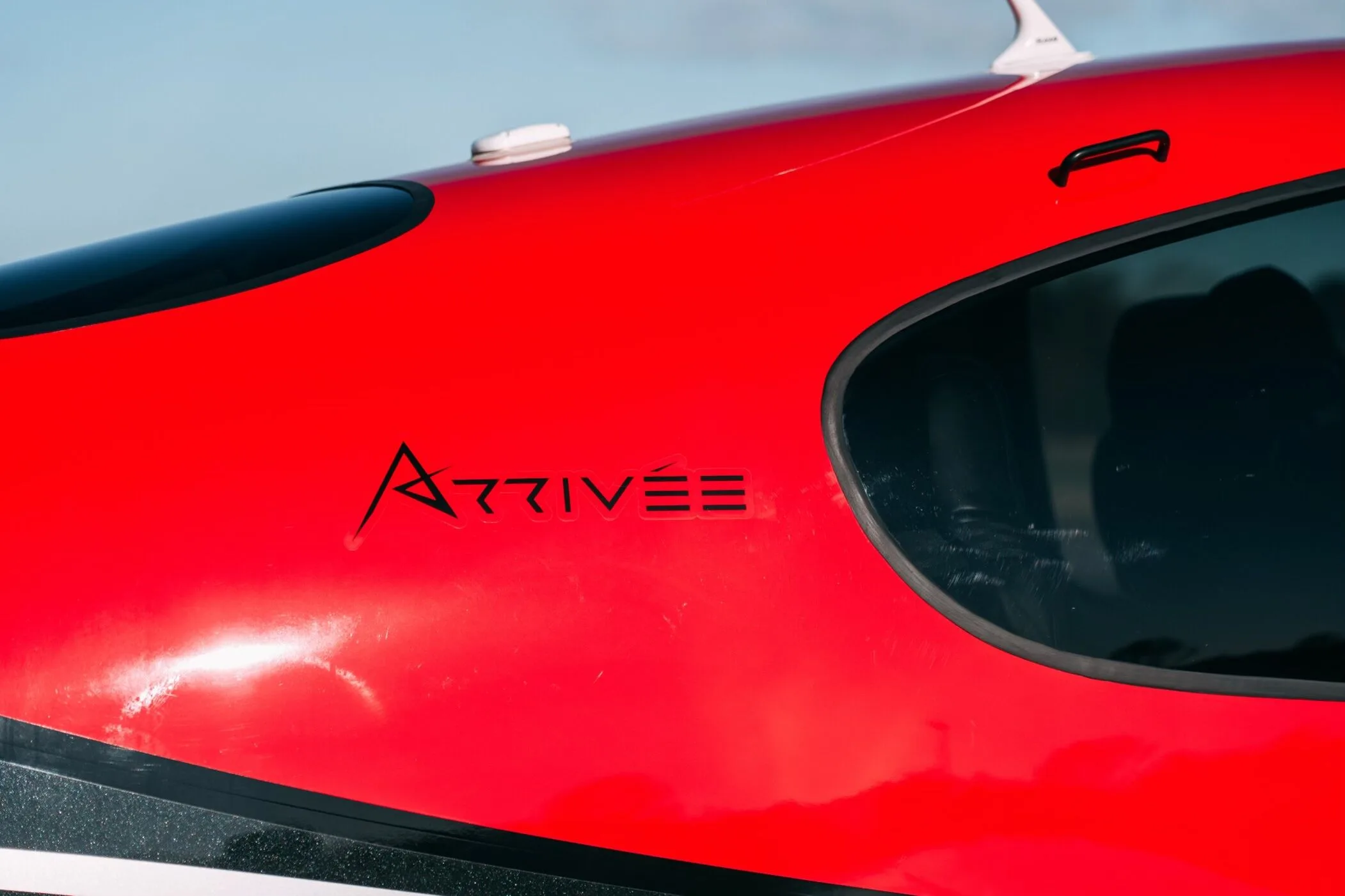 A close-up of the red fuselage of the Cirrus SR22T aircraft, showing the "ARRIVÉE" branding.