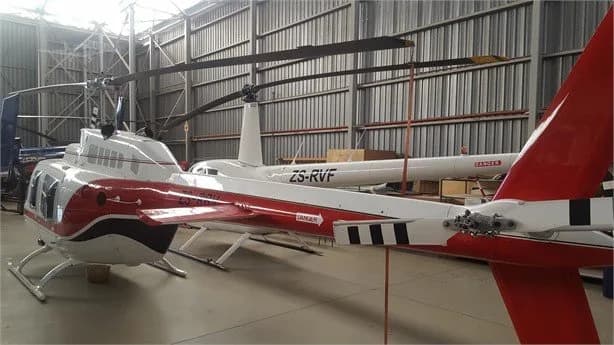 Rear view of a Bell Jet Ranger helicopter with registration ZS-RDV inside a hangar.
