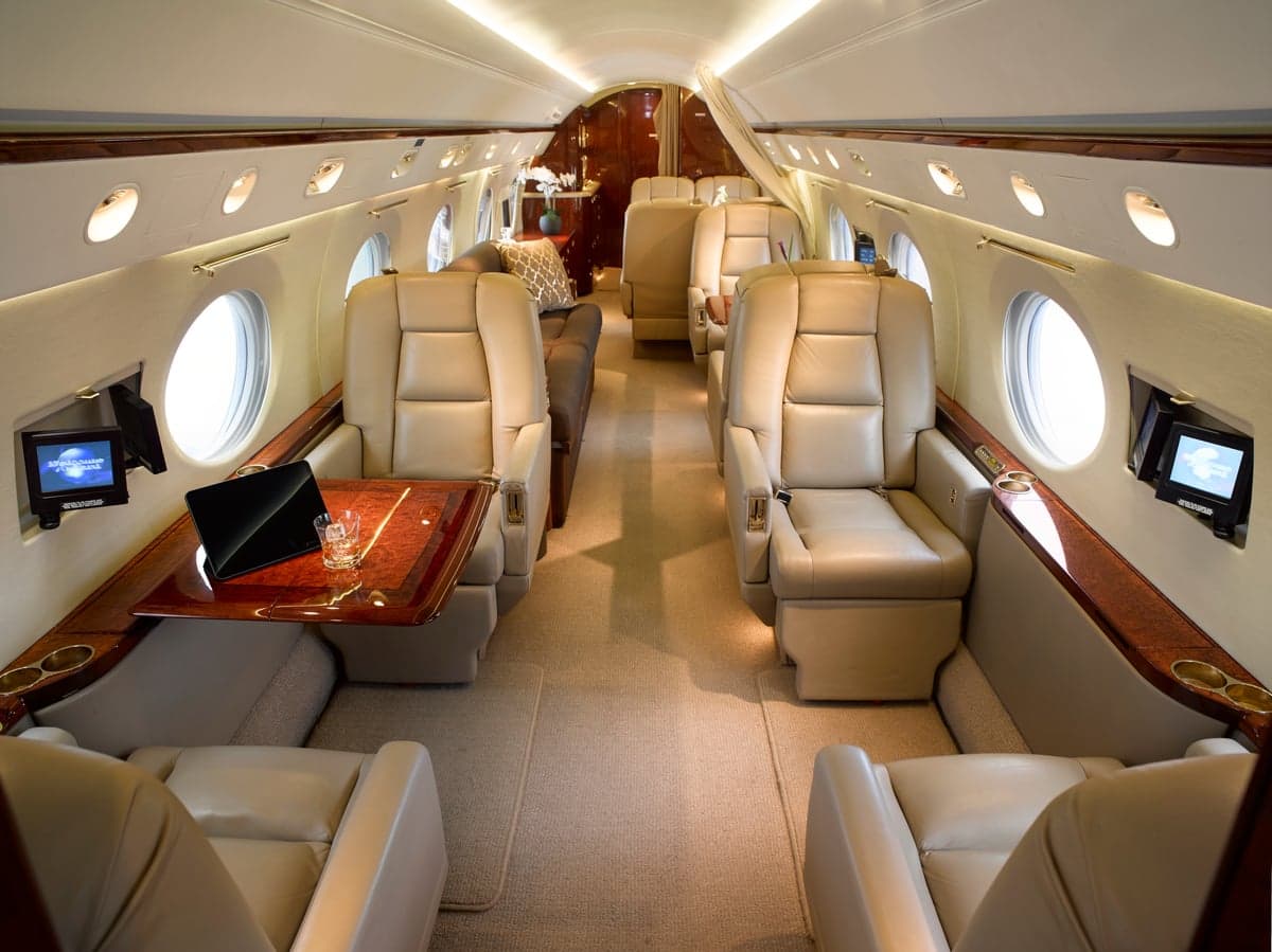 Interior view of the aircraft cabin with leather seats and wood trim.
