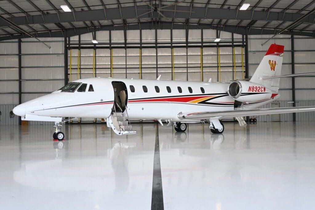 A Citation Sovereign aircraft with tail number N892CW is parked in a hangar with the door open.
