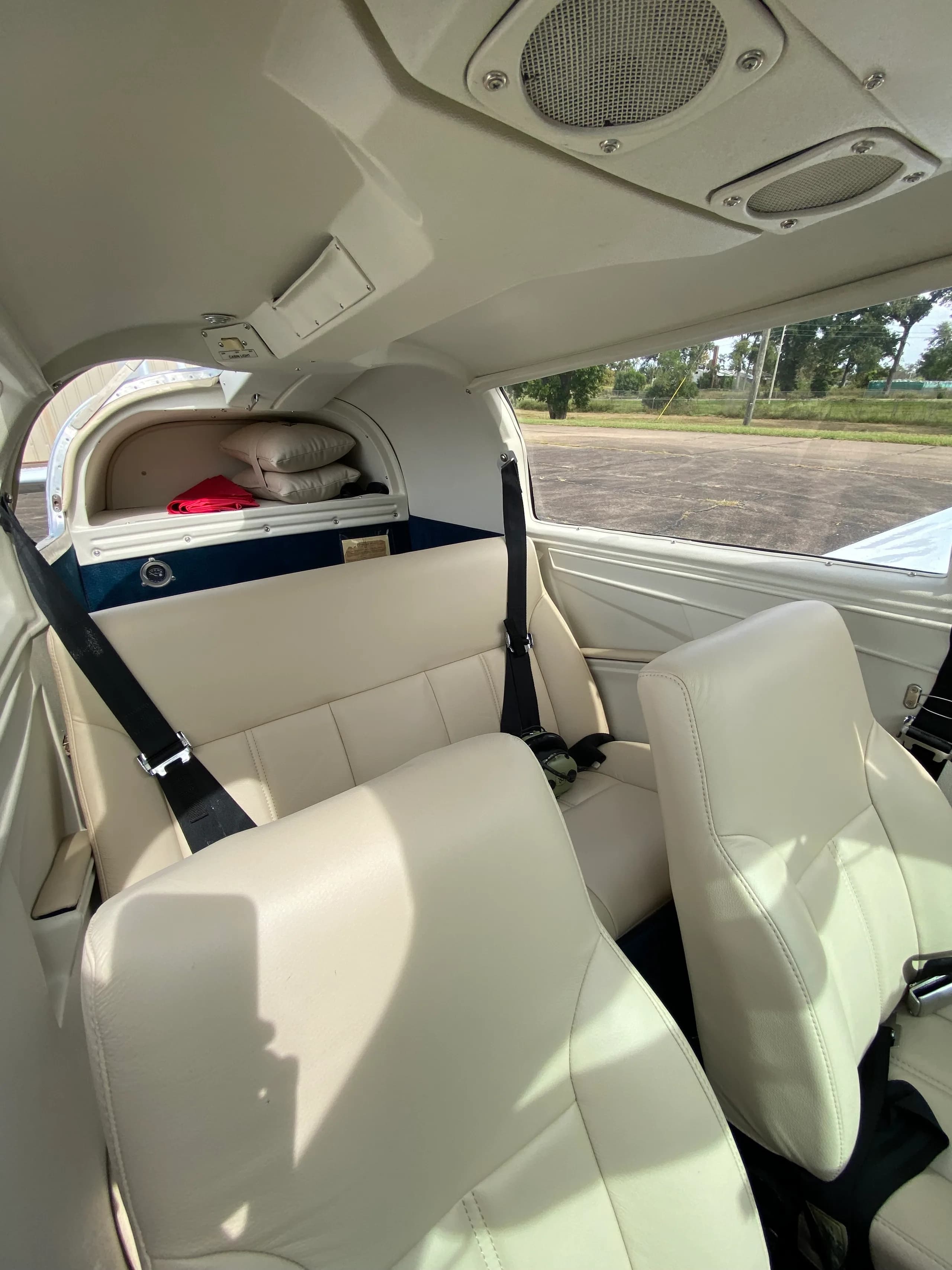 View of the cream-colored leather passenger seats and rear cargo area inside the aircraft cabin.