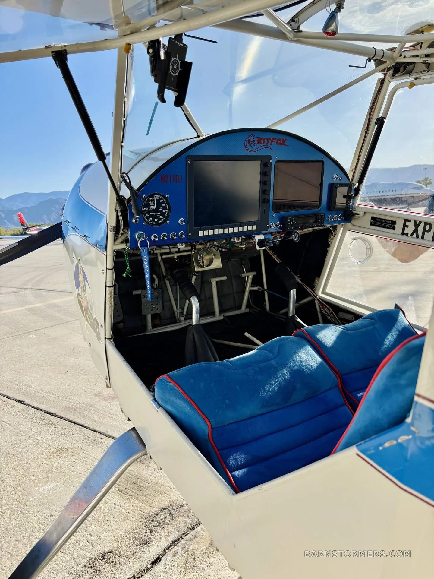 The cockpit of a Kitfox aircraft with blue seats, a blue instrument panel, and a view of mountains outside.