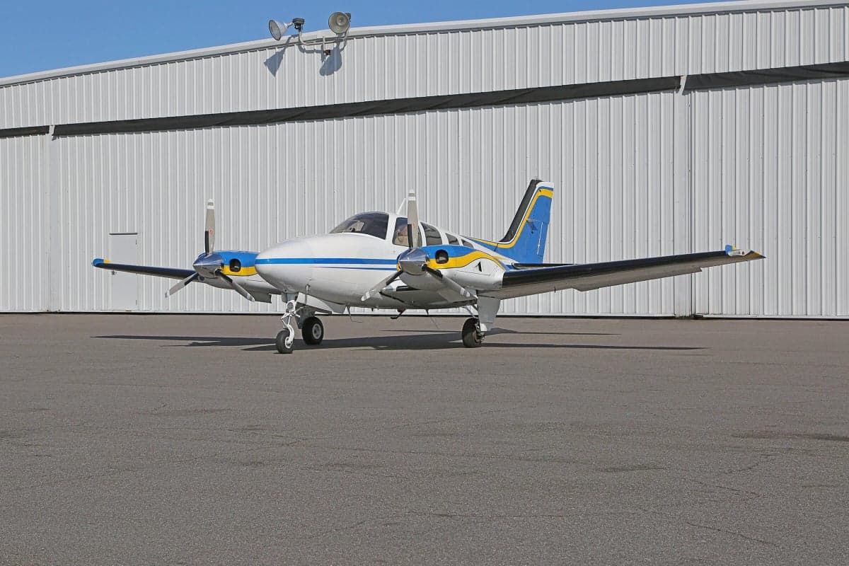 A Piper PA-31 Navajo Chieftain aircraft parked on the tarmac in front of a hangar.
