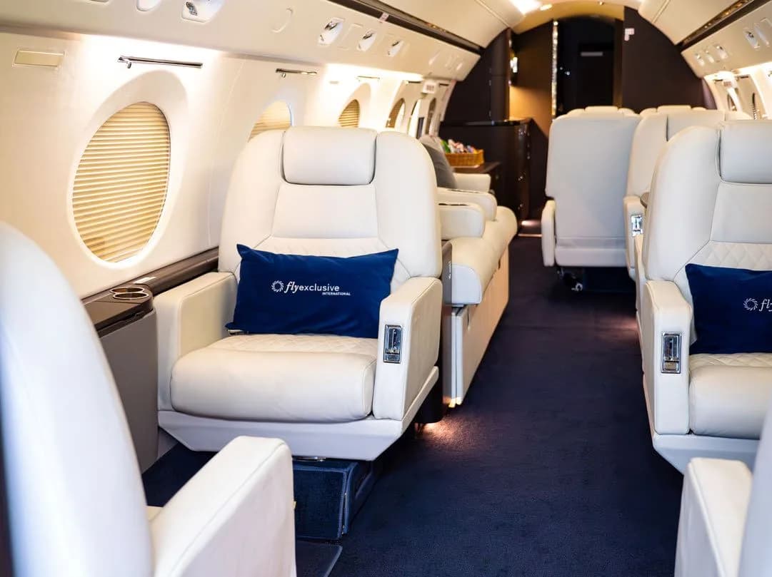 Aircraft interior with white leather seats and blue carpet.