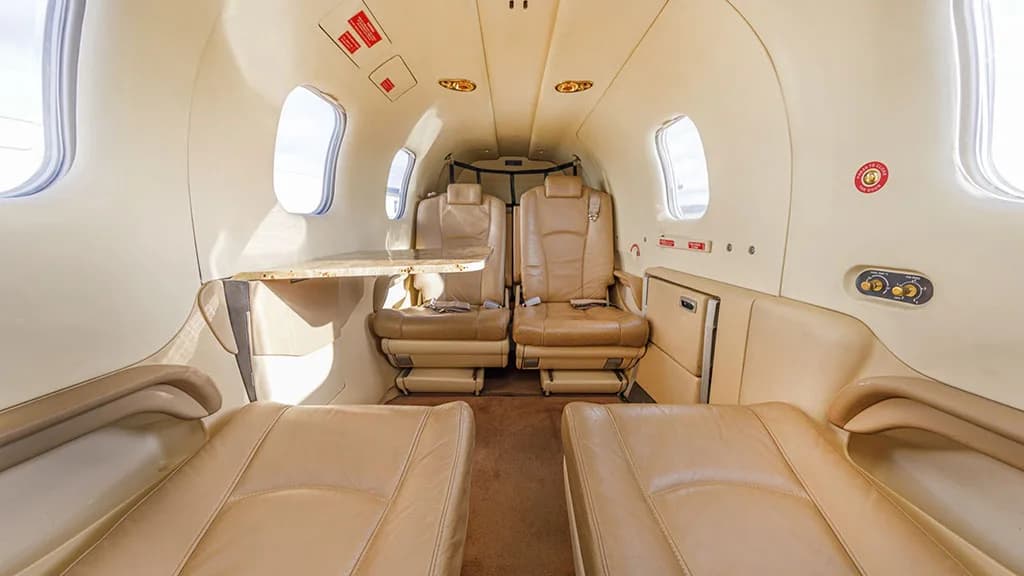 The luxurious tan leather interior cabin of a TBM aircraft, featuring facing seats and a small table.