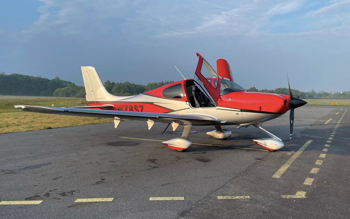 A Cirrus SR22G6 aircraft with registration N78SZ is parked on the tarmac with its doors open.