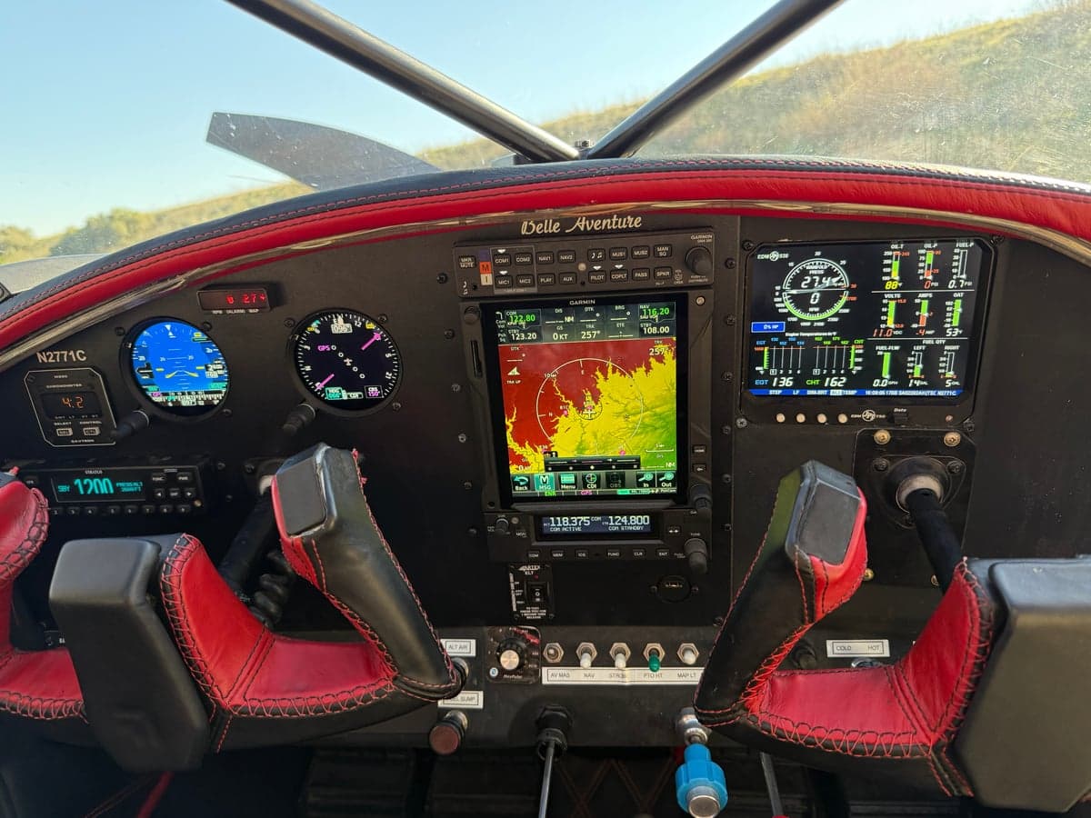 The aircraft's cockpit features a modern avionics suite and red-stitched leather trim.