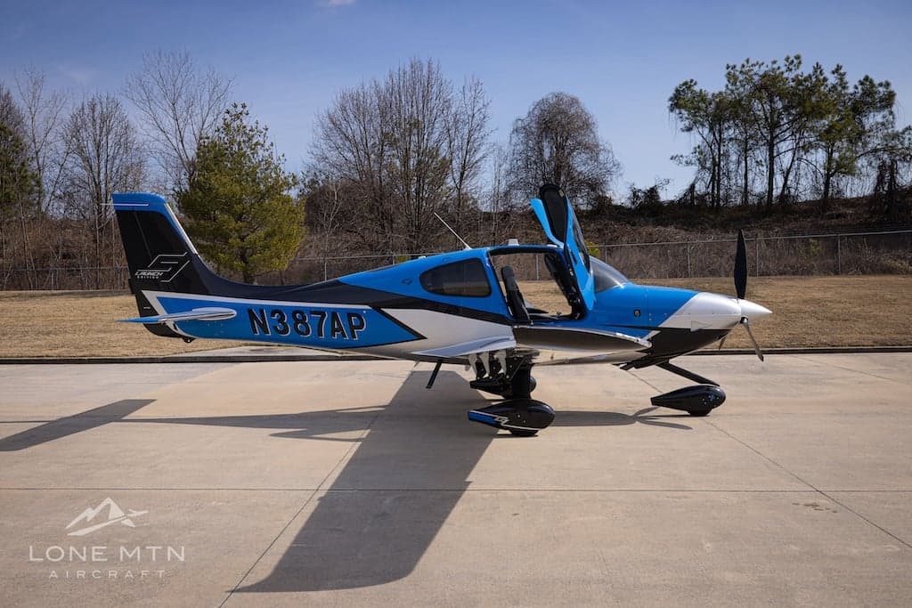Cirrus SR22T with blue and silver paint scheme on the ramp with doors open.