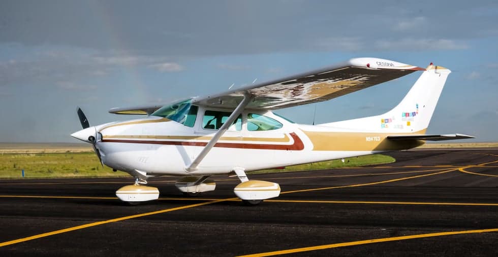 A Cessna aircraft with a white and gold paint scheme parked on the tarmac.