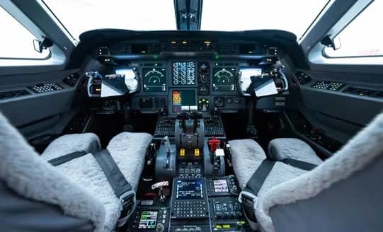 Cockpit of a private jet with instrument panel and seats.