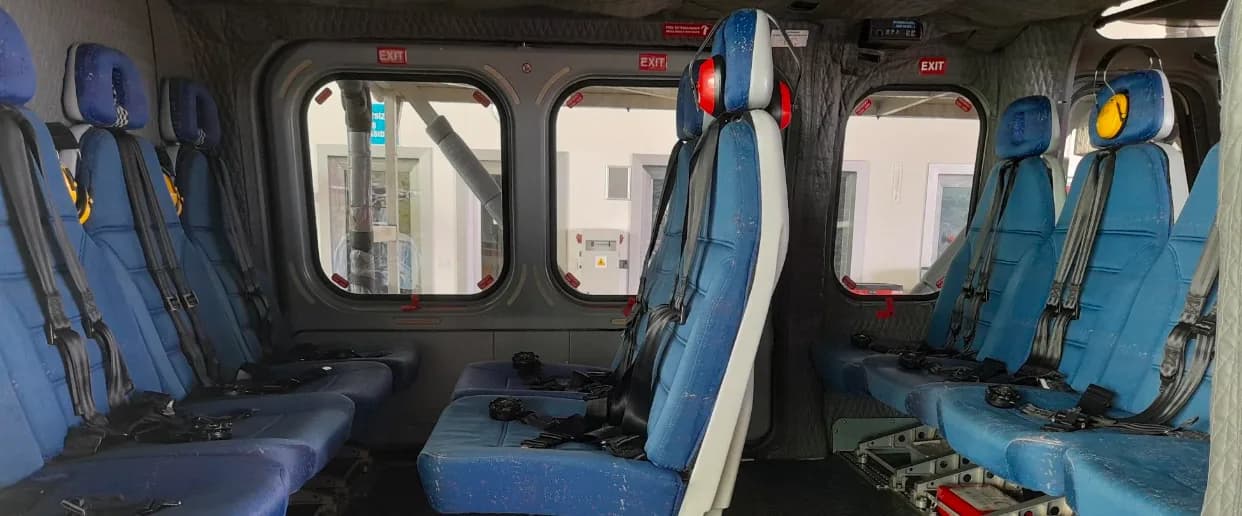 Interior view of the helicopter cabin with blue seats and headsets.