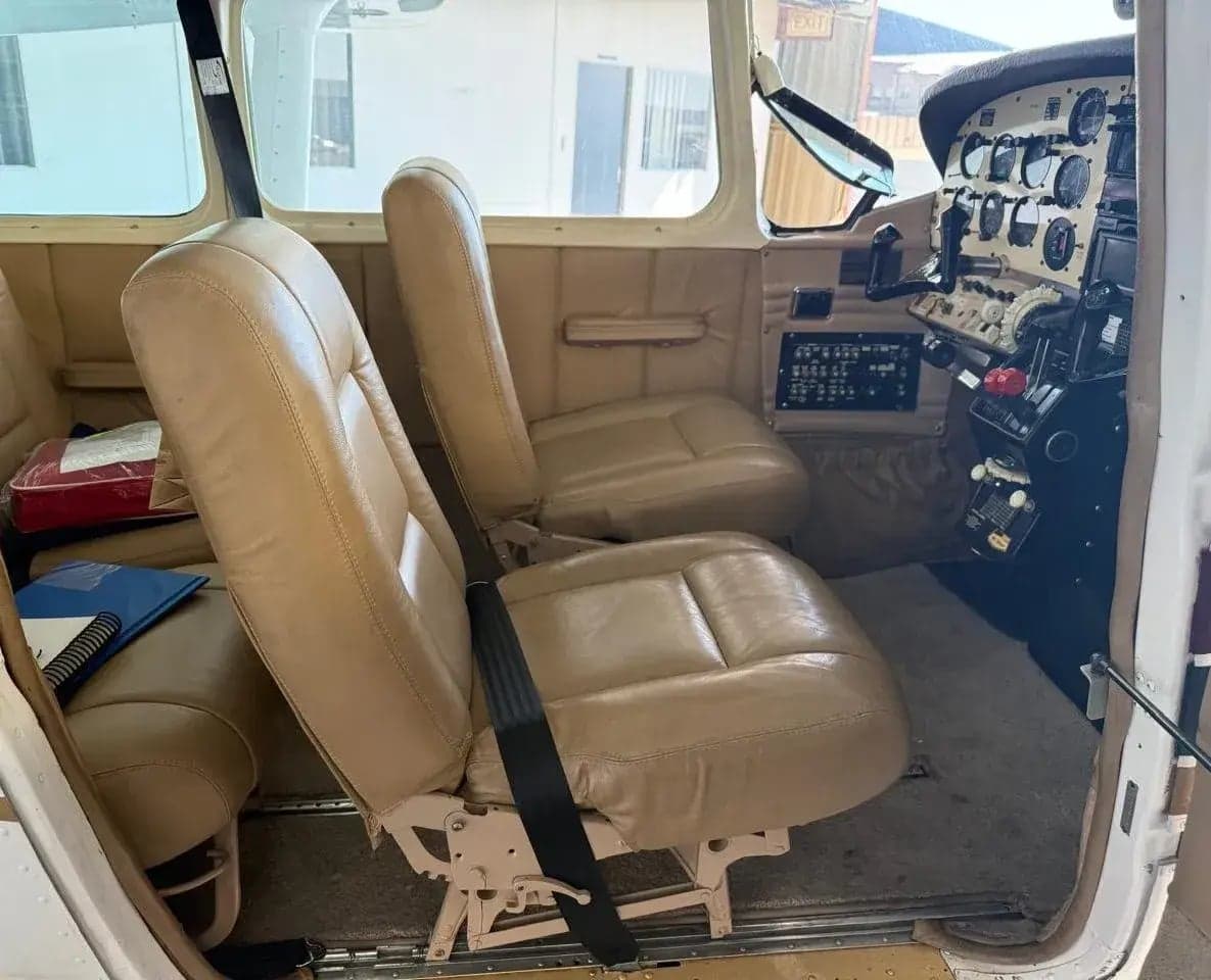 View of the aircraft's front cabin with two tan leather seats and a partial view of the cockpit instruments.