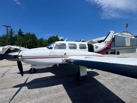 A white and maroon twin-engine aircraft, N30DF, parked on the tarmac with the door open.