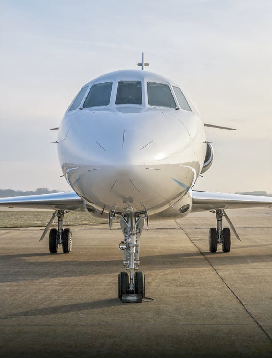 Front view of a white Falcon jet on the tarmac.