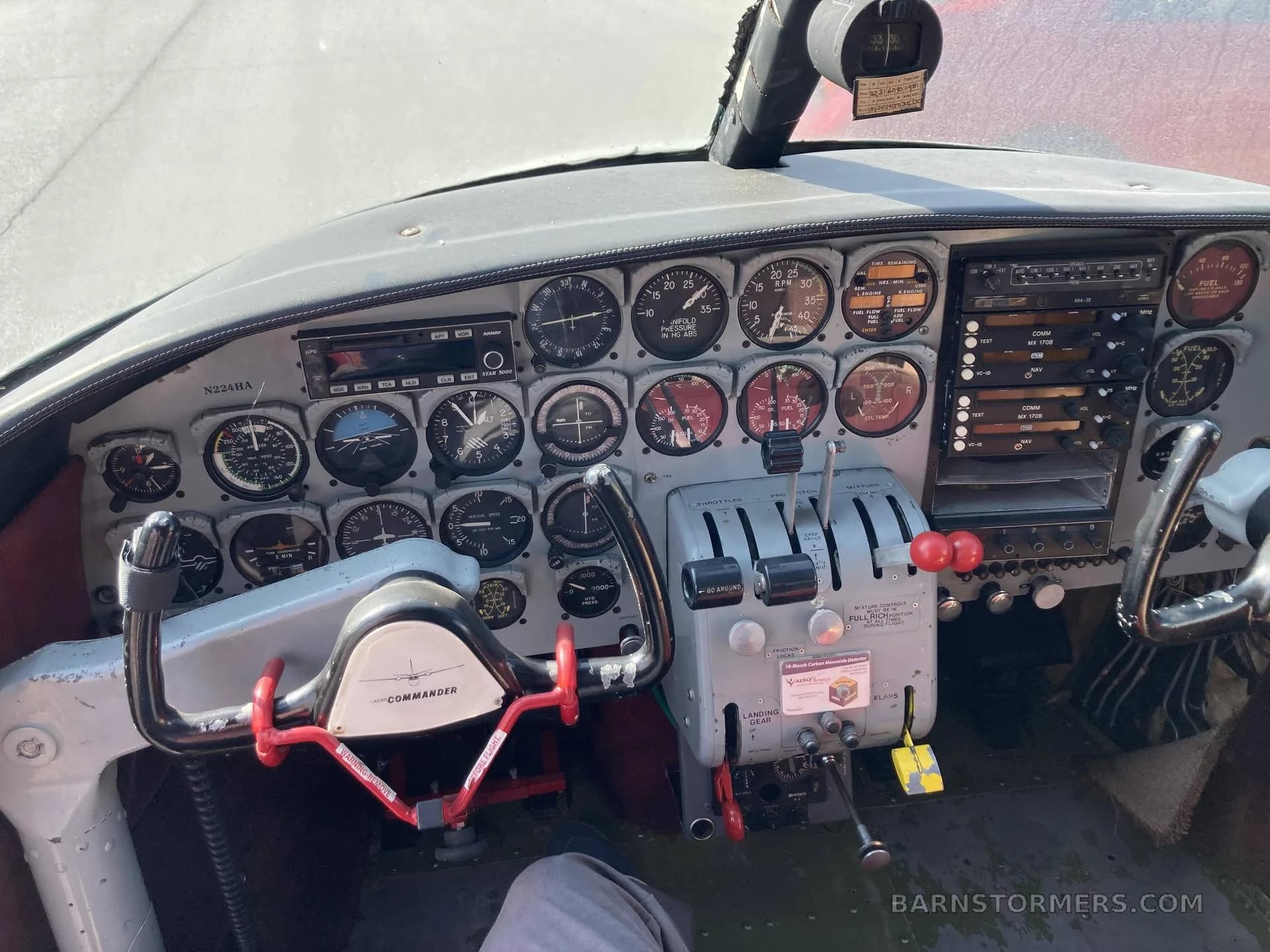 The cockpit of a Commander aircraft, showing the instrument panel, yokes, and throttle quadrant.