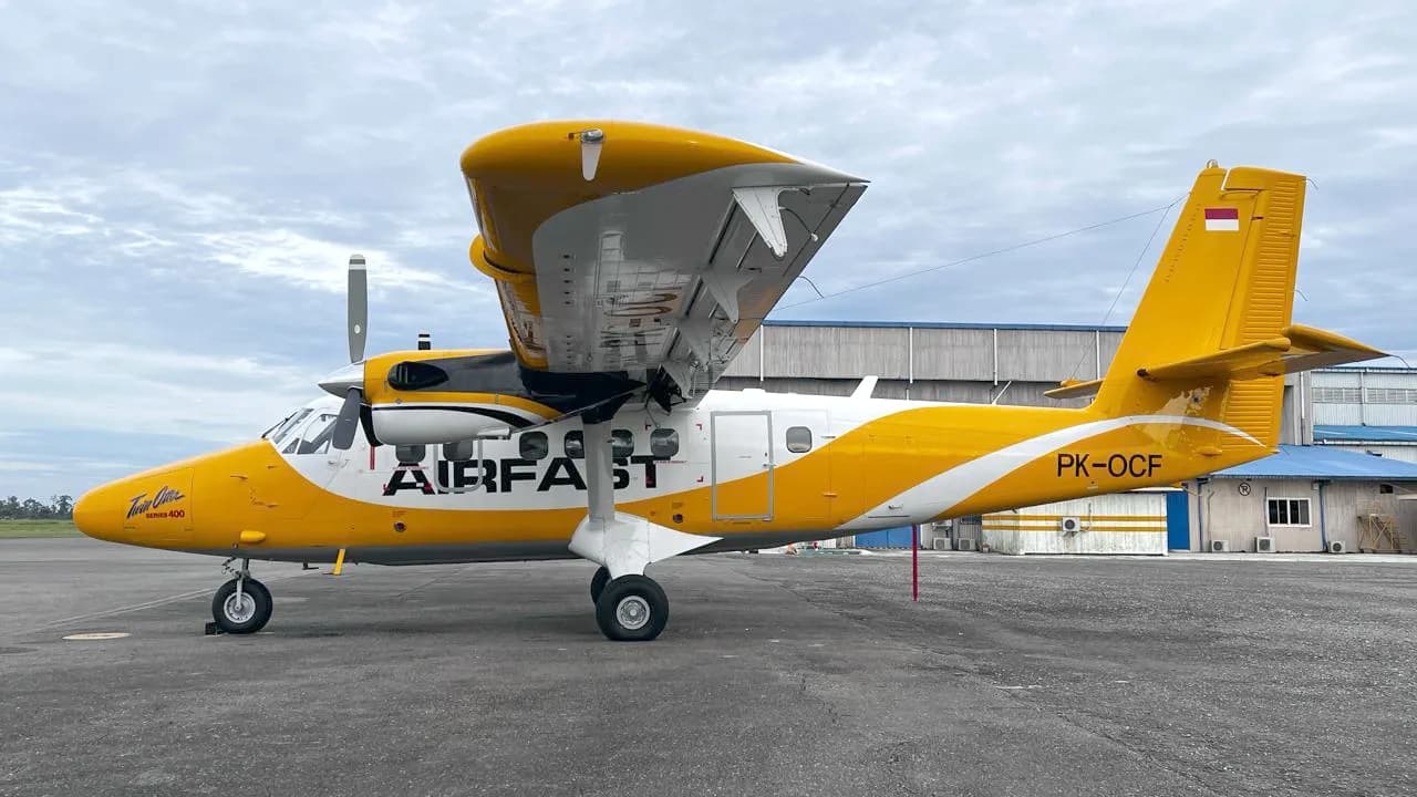 Side view of PK-OCF Twin Otter parked on the tarmac.