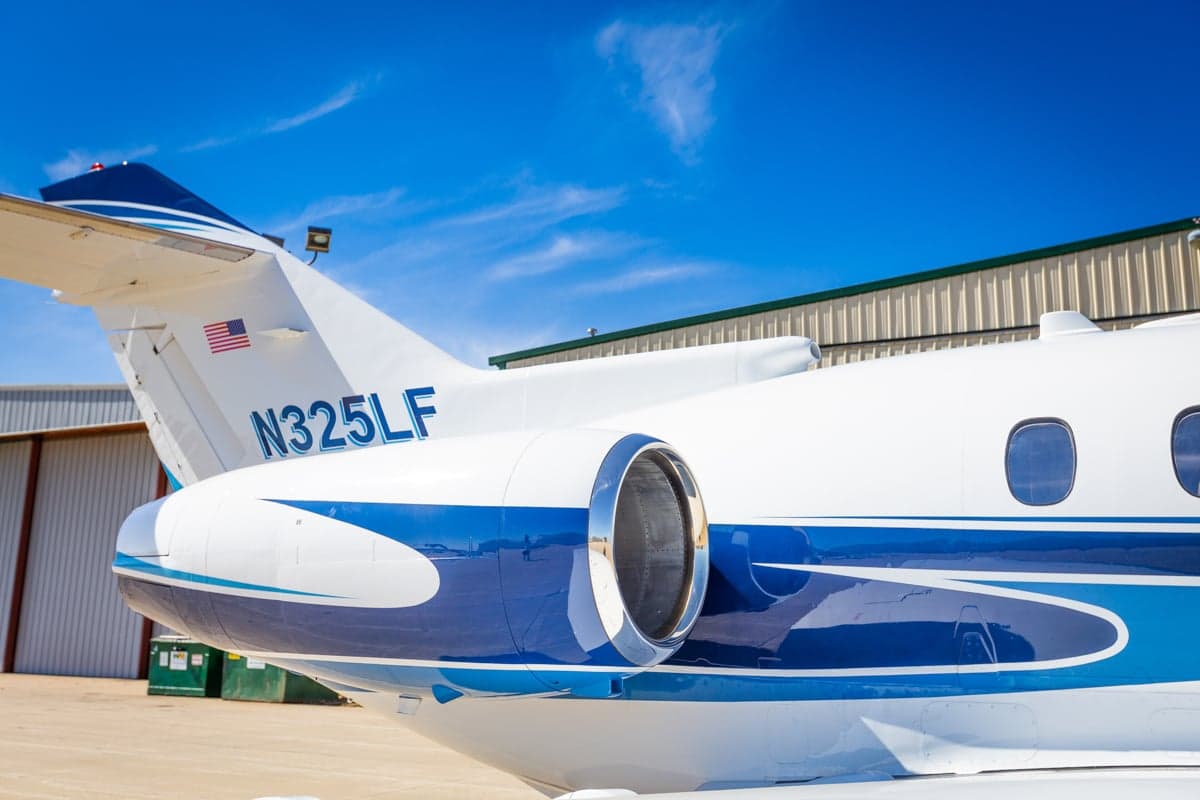 Close up of the tail and engine of a white and blue jet with the registration number N325LF.