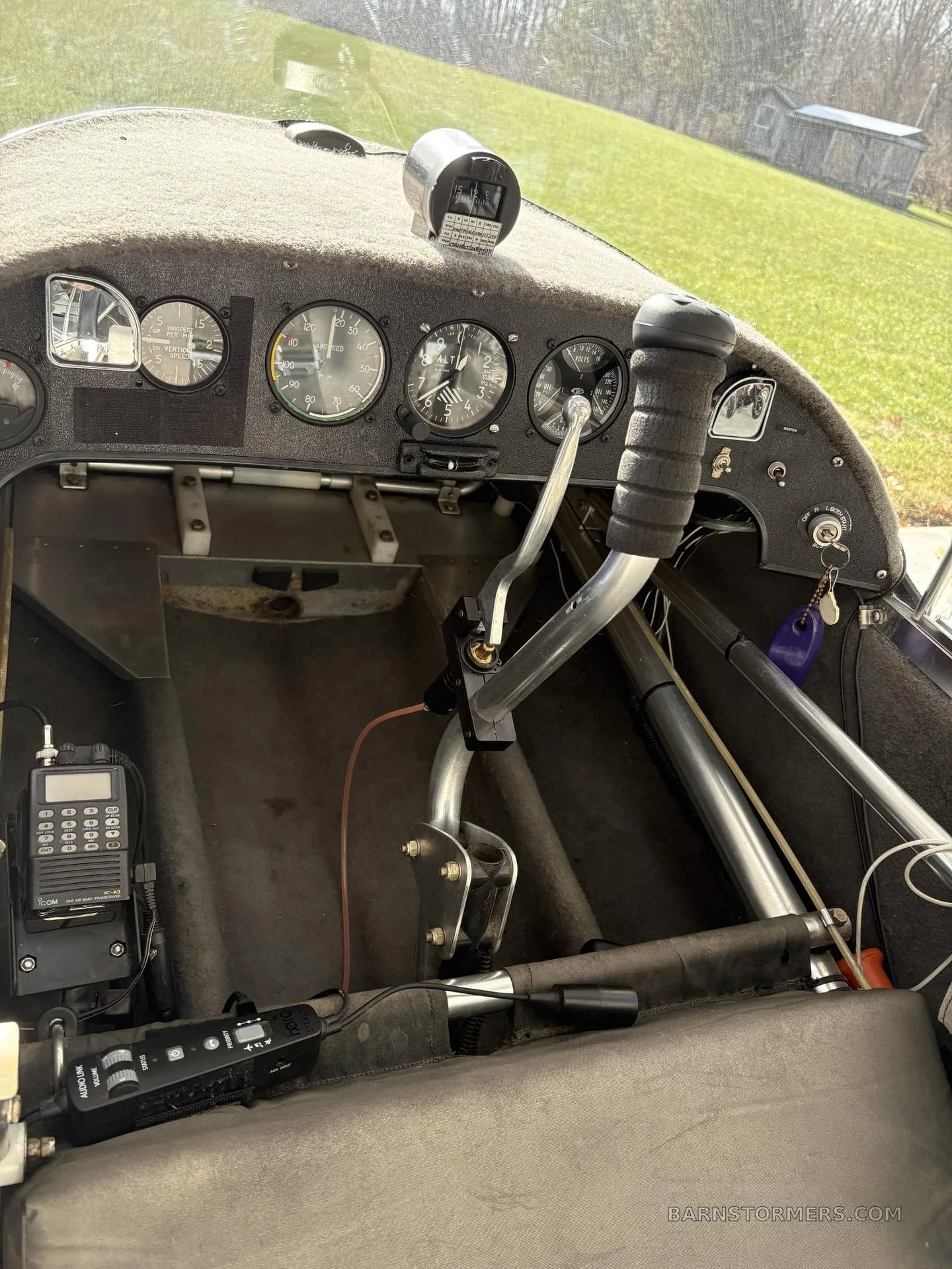 The cockpit of an ultralight aircraft showing the instrument panel, control stick, and radio.