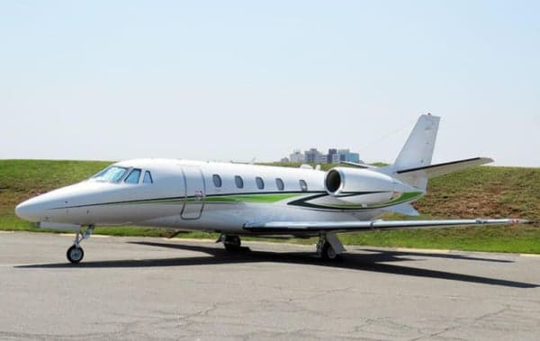 A Cessna Citation CJ3+ aircraft is parked on the tarmac with a white and green paint scheme.