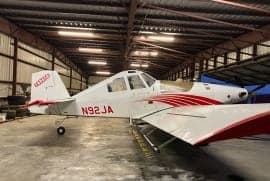Side view of a white and red Air Tractor crop duster with tail number N92JA inside a hangar.