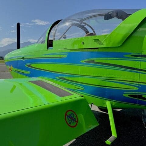 Close-up of the side of a green aircraft with blue accents and a "NO STEP" warning.