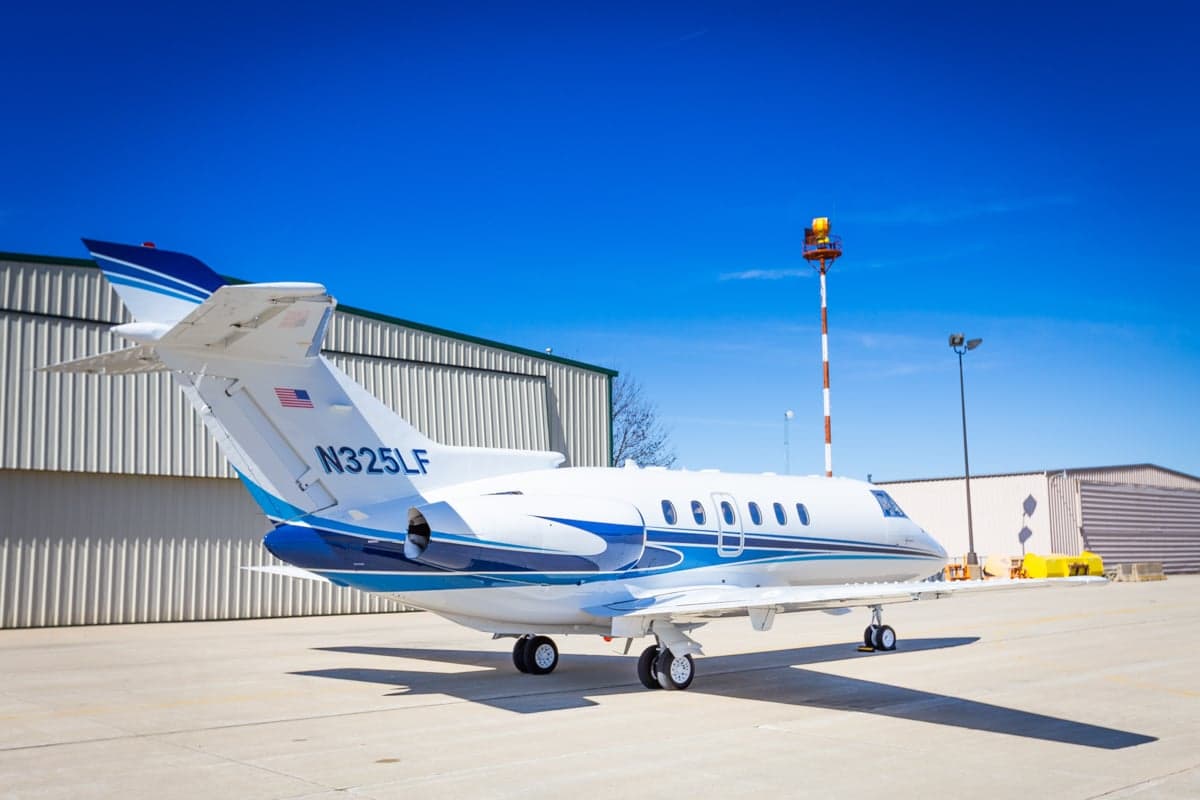 The tail of a white and blue jet with the registration number N325LF is visible on the tarmac.