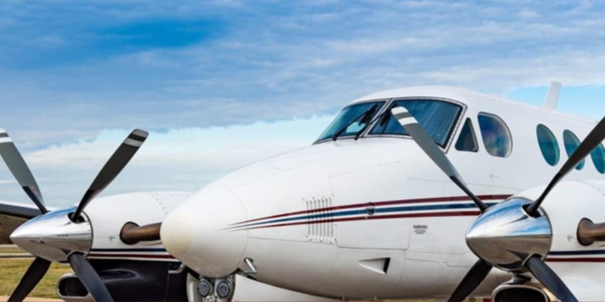 Close up of the nose and propellers of a white aircraft.