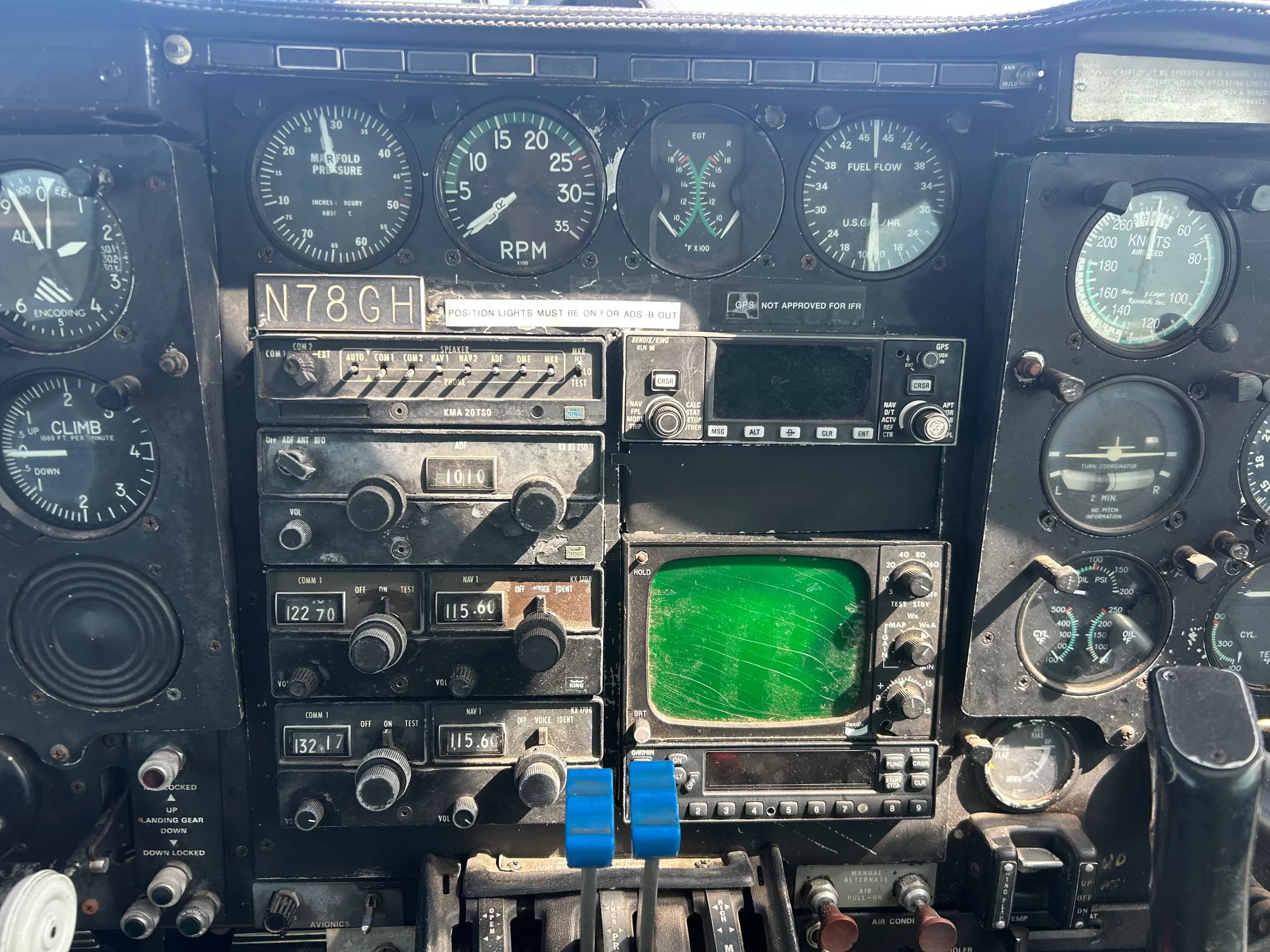 A close-up view of the center cockpit instrument panel in aircraft N78GH, featuring radios and a green radar screen.