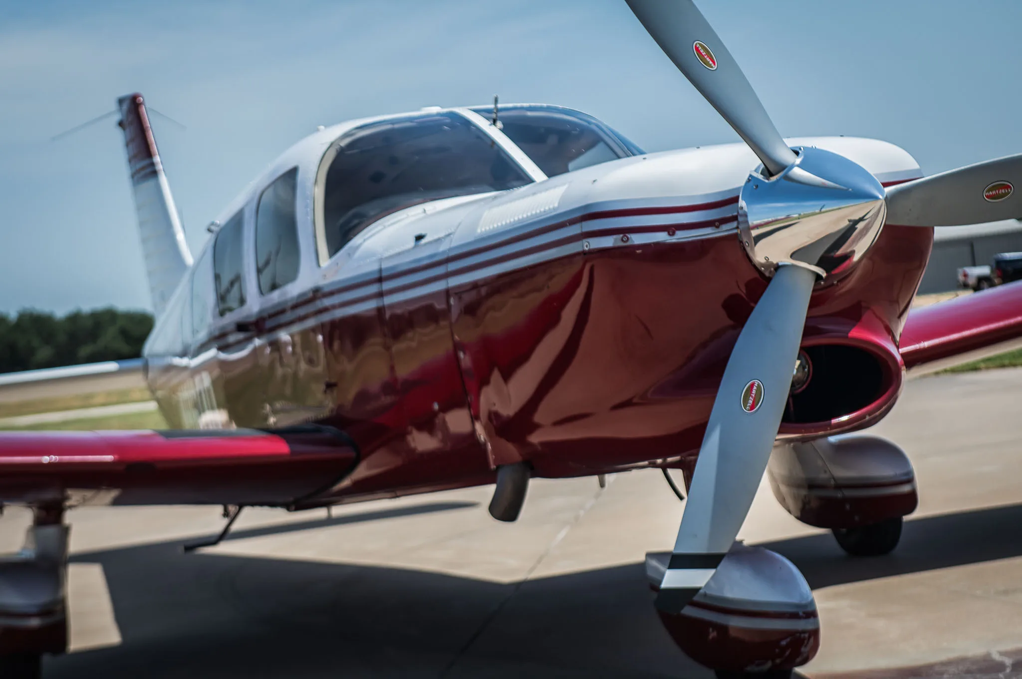 A low-angle close-up of the front of the red and white aircraft, highlighting the propeller.