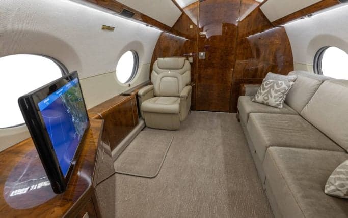 Aircraft cabin interior with a table and leather seats.