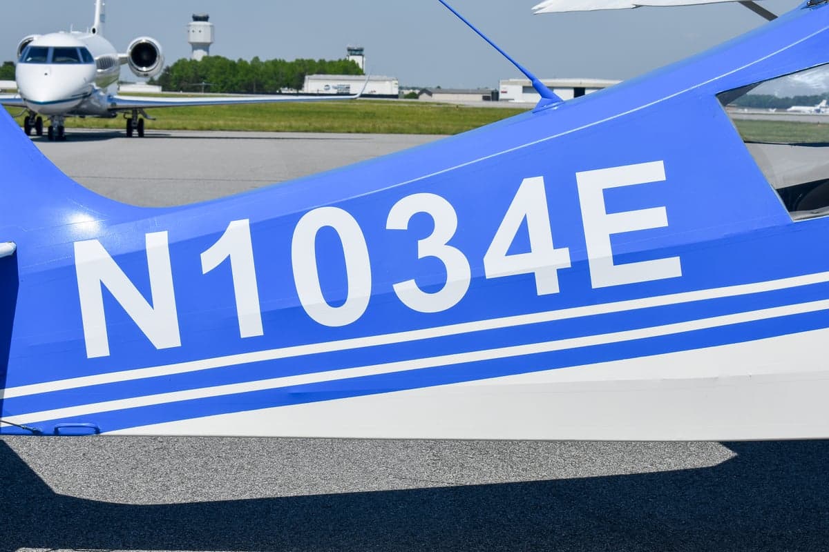 Rear view of a blue and white aircraft with tail number N1034E on the tarmac.