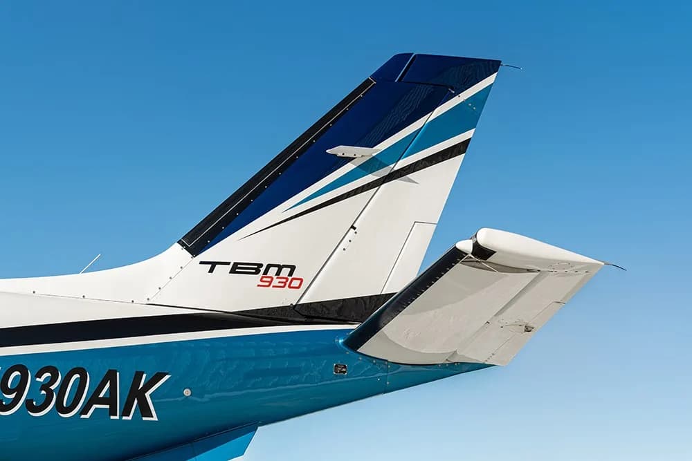 A close-up view of the tail section of the TBM 930 aircraft N930AK, showing the blue and white livery.