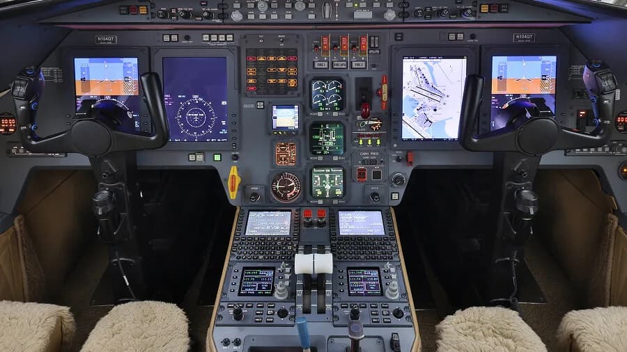The modern cockpit of a business jet with multiple digital displays and control yokes.