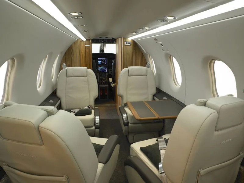 Forward view of the cabin with white leather seats and wood trim.