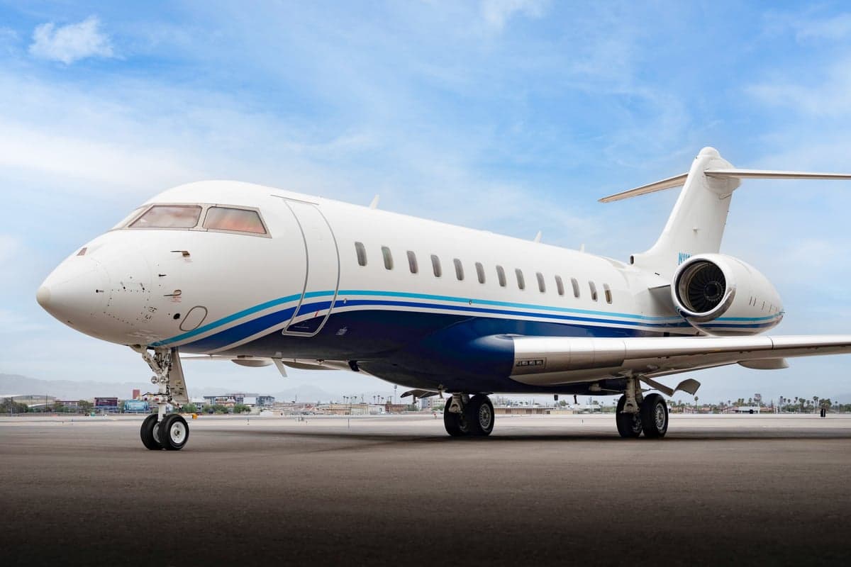 A Bombardier Global Express aircraft parked on the tarmac with a blue and white paint scheme.