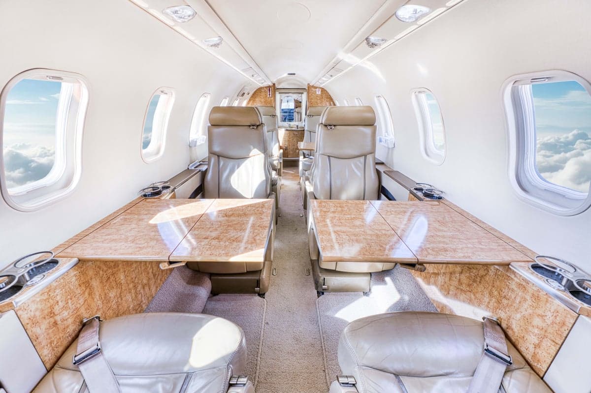 The interior of the aircraft features leather seats and wood-grain tables.