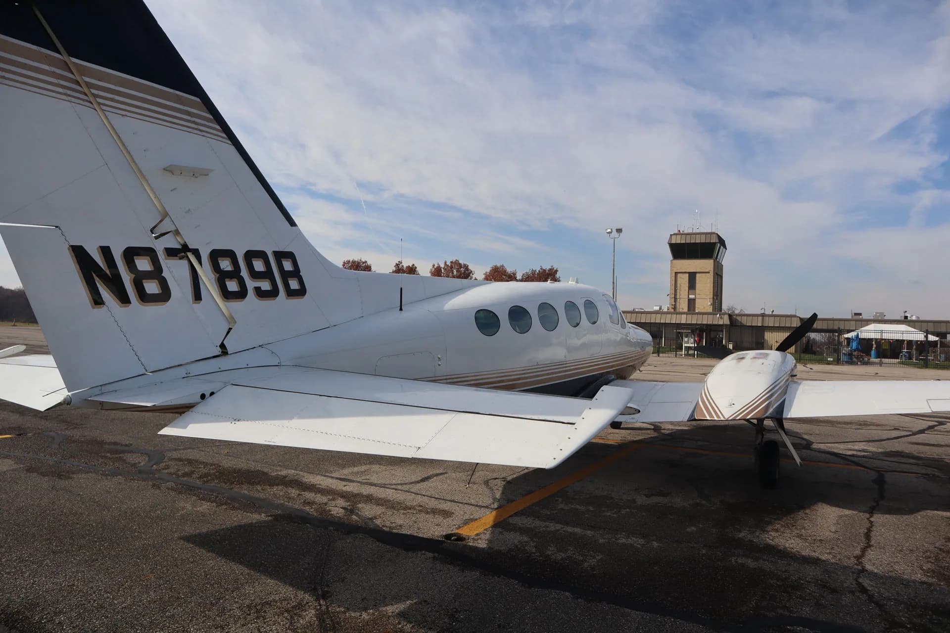 The tail of the N8789B aircraft is visible on the tarmac with an airport control tower in the background.