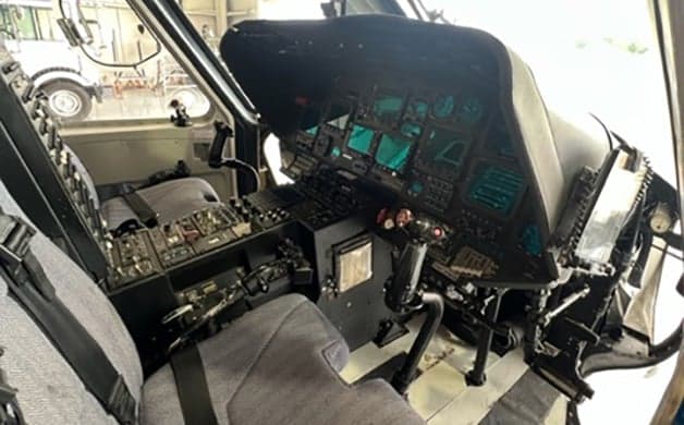 AgustaWestland AW139 helicopter in a hangar with blue, green, and white paint scheme.
