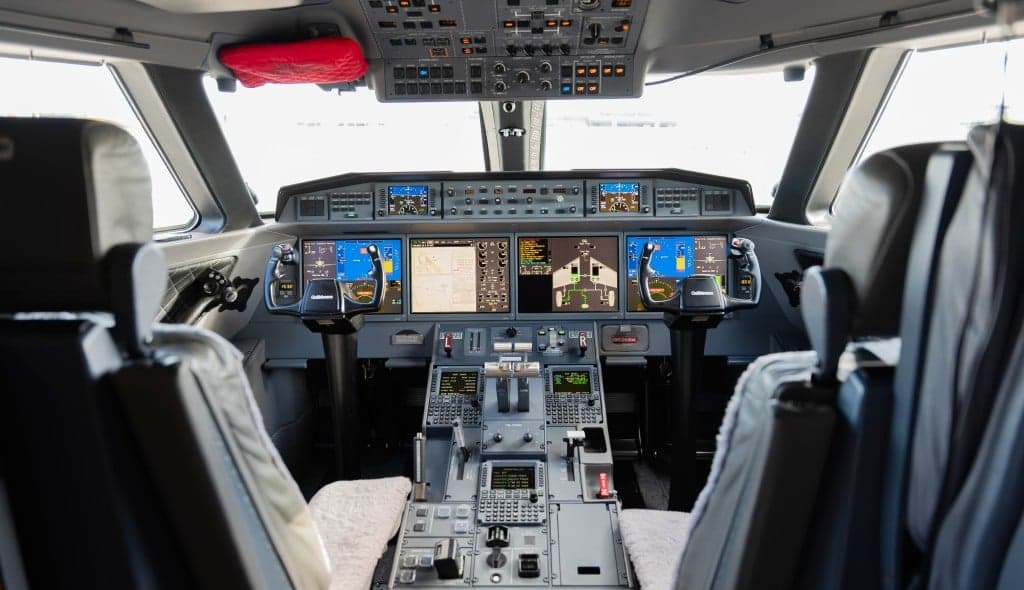 The interior of the aircraft with beige leather seats, wood paneling, and a sofa.