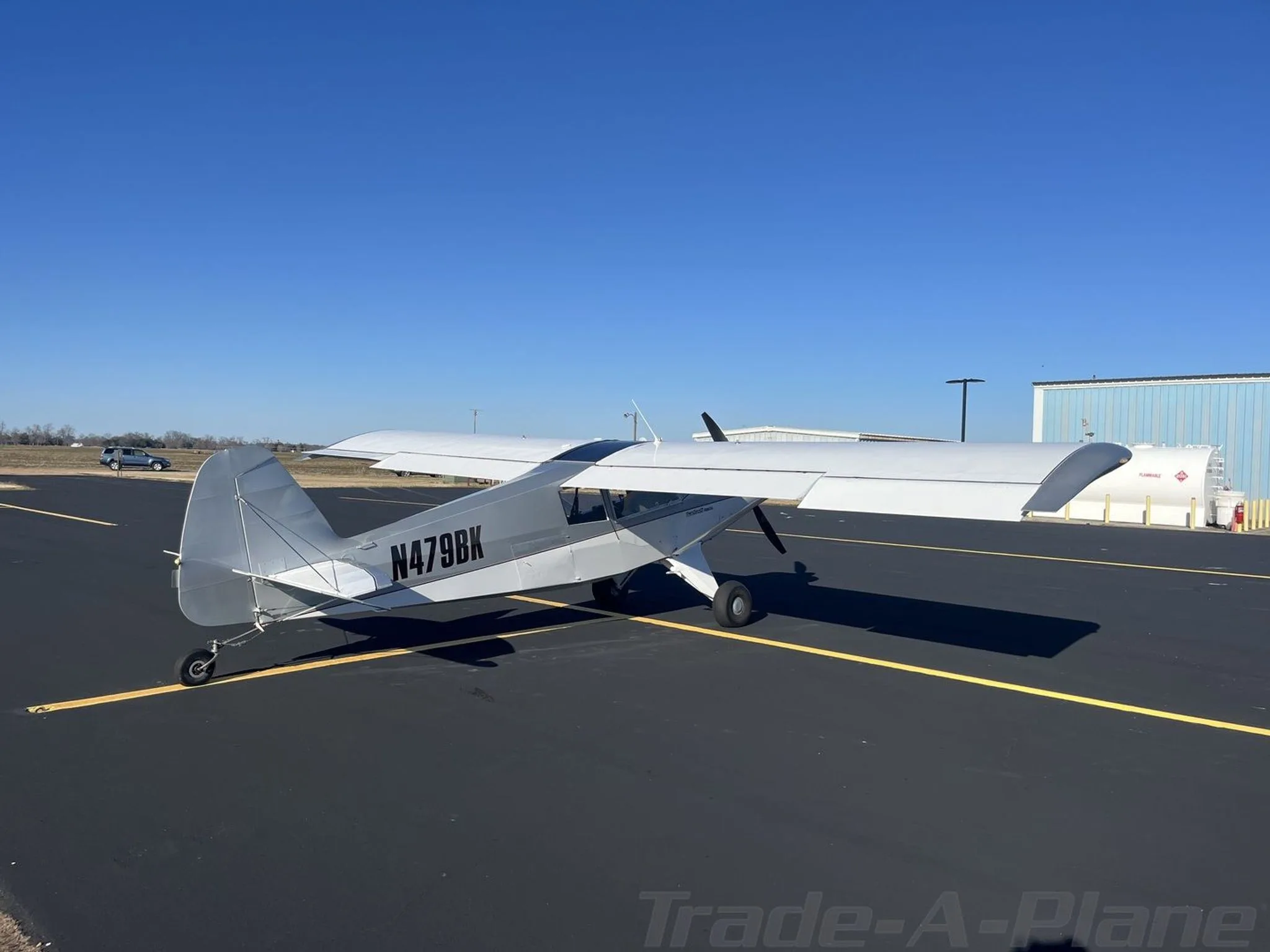 Three-quarter rear view of a silver Bearhawk Patrol aircraft with registration N479BK on an asphalt tarmac.