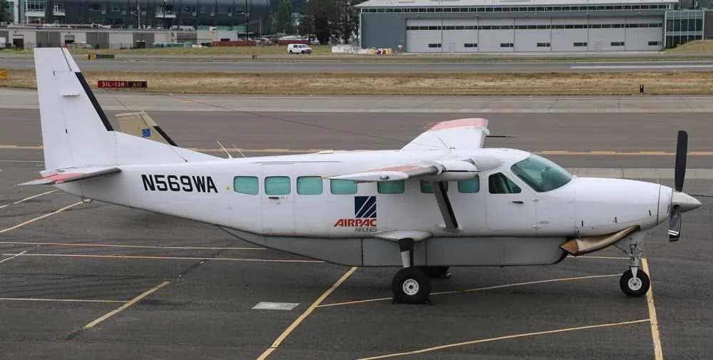 A white Cessna Caravan is parked on the tarmac at an airport.