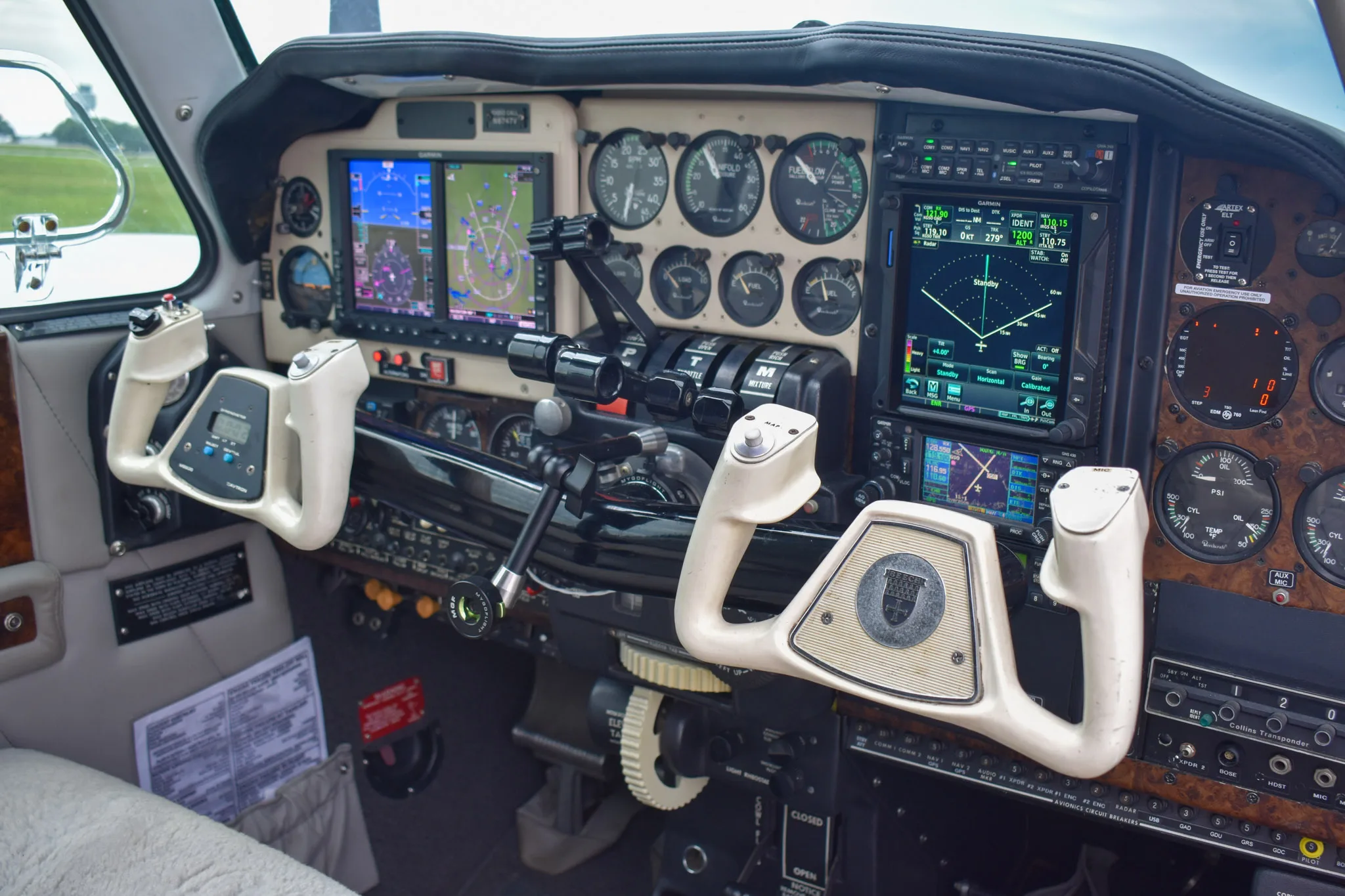 A close-up view of the Beechcraft Baron cockpit instrument panel with dual yokes and modern avionics displays.