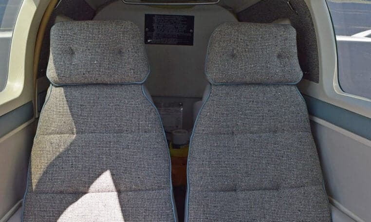 The aircraft's cabin interior shows two rows of grey patterned seats from a rear-facing perspective.