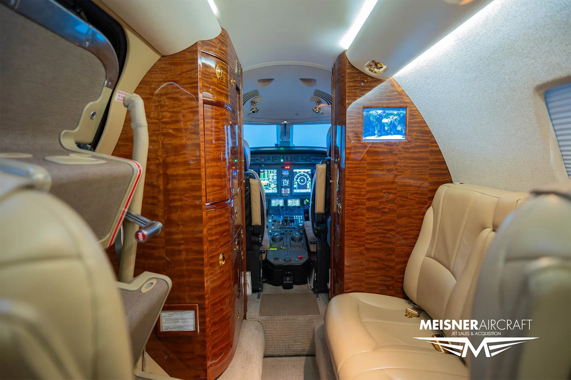 A view from the rear of the business jet cabin looking towards the cockpit, showing the aisle and cabin amenities.