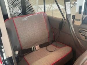 A gray fabric seat with red trim is shown inside the aircraft cabin.
