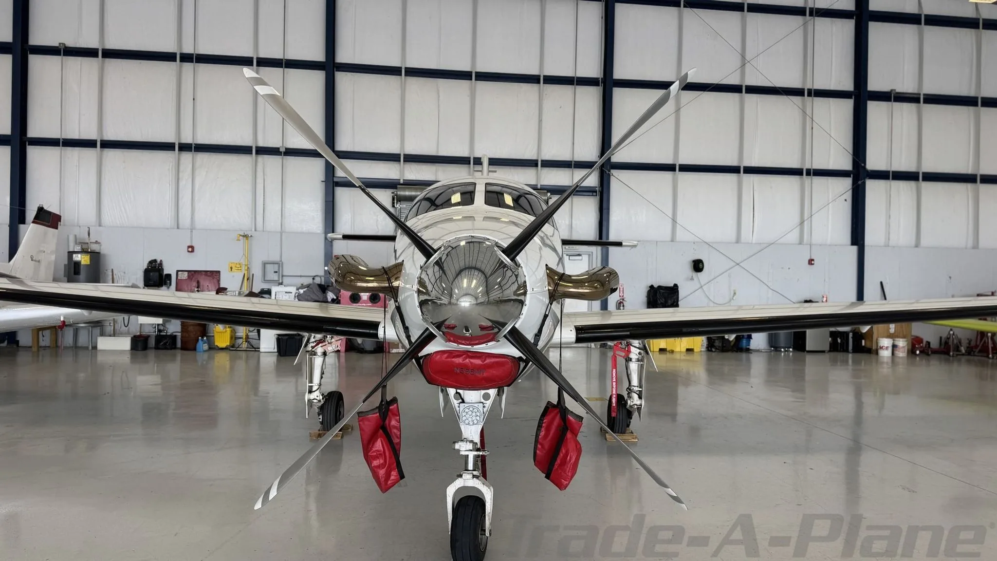 Front view of a white Epic LT aircraft with a dark red stripe, parked in a hangar.